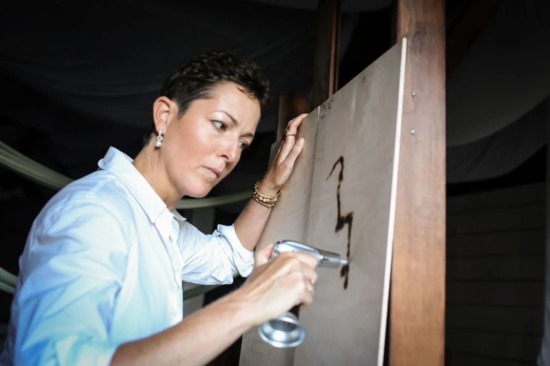 Louise using fire to make marks on a wooden panel