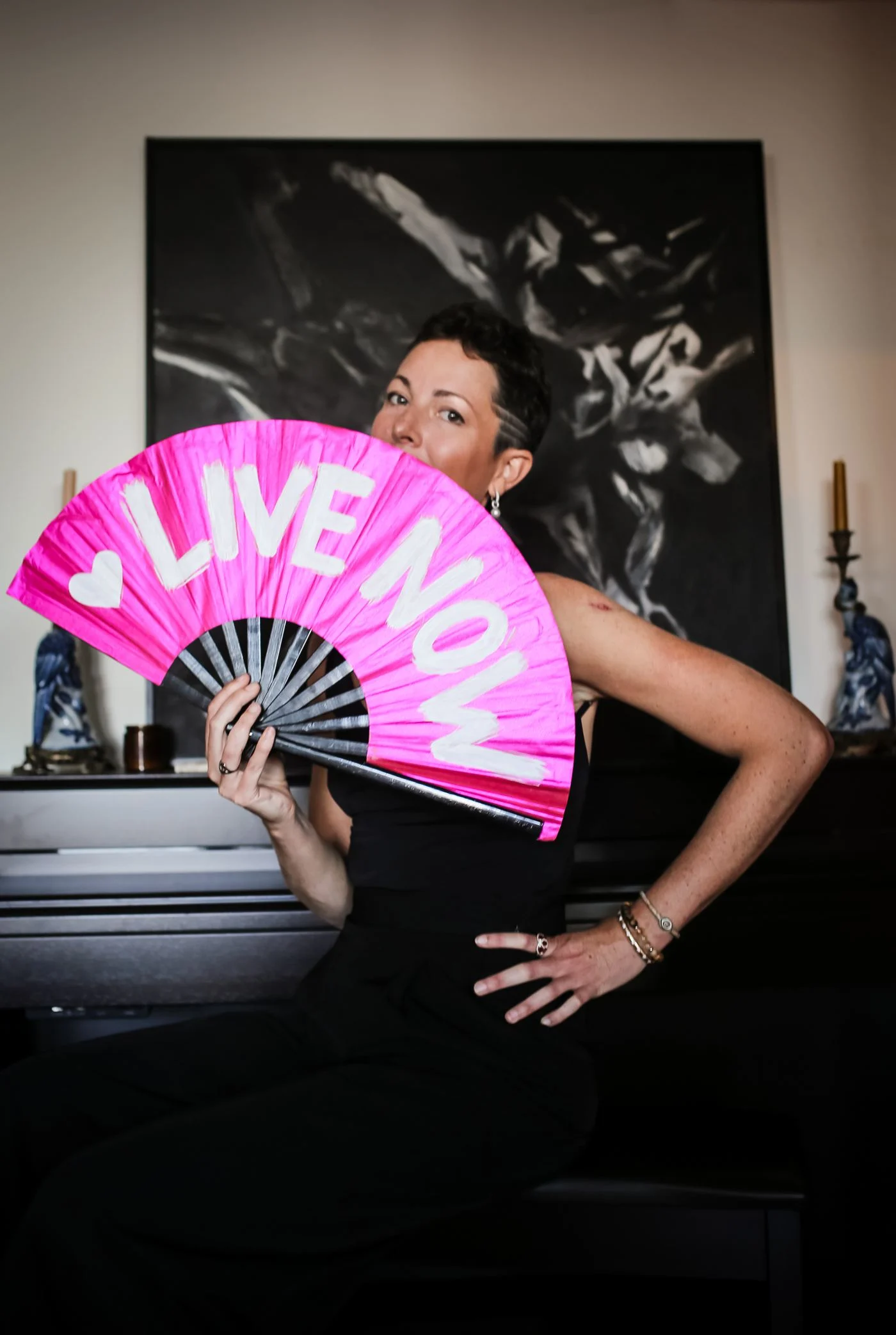 Louise looking over a pink fan that reads Live Now